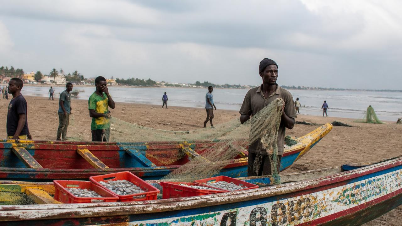 Pêcheurs guinéens et pirogues colorées sur une plage de Conakry